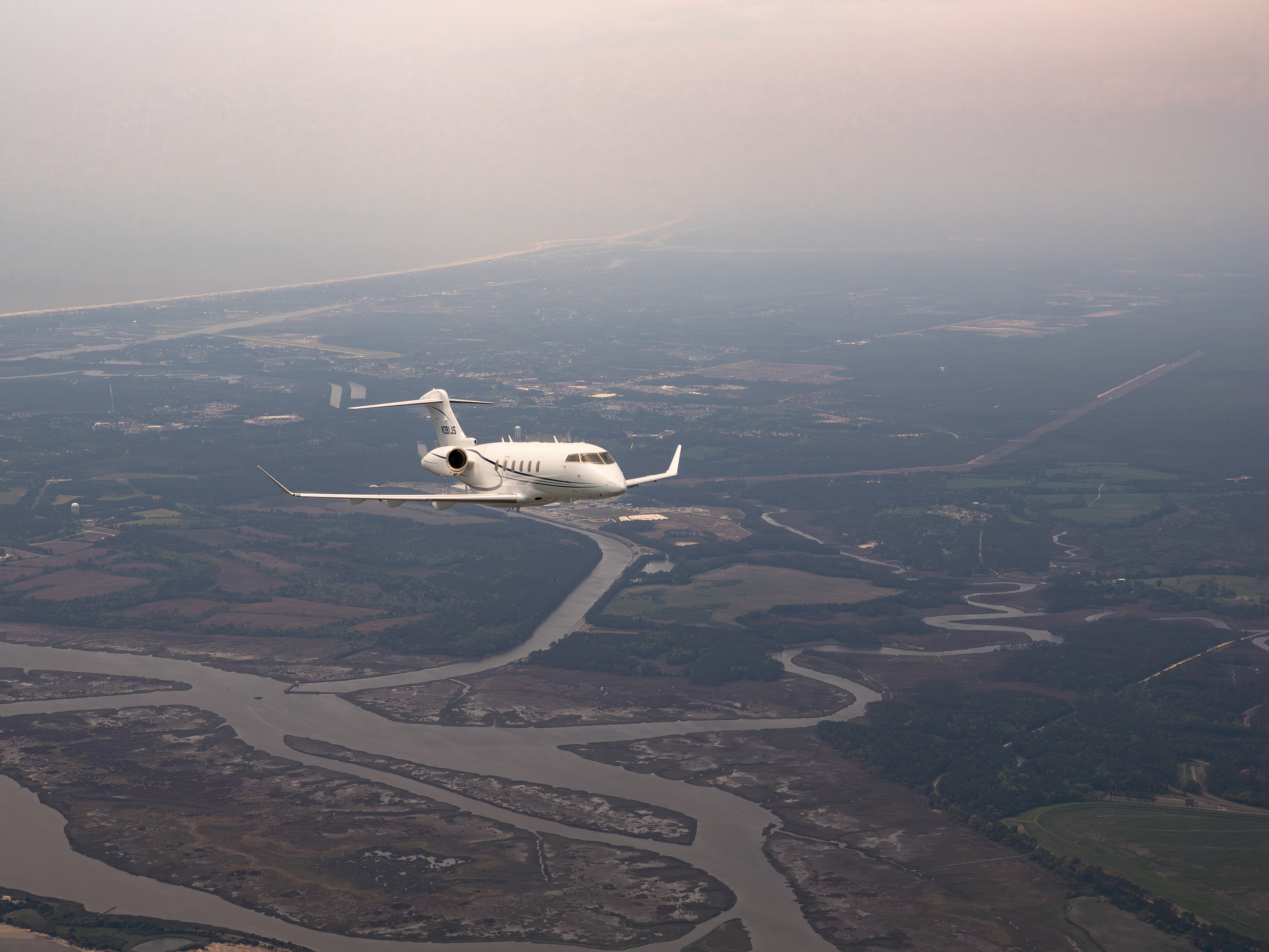 flyExclusive Challenger 350 air-to-air over a river