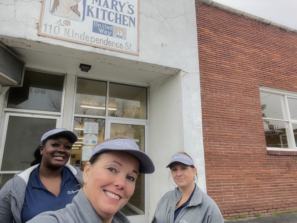 Three flyExclusive employees in branded caps outside Mary’s Kitchen in Kinston, North Carolina