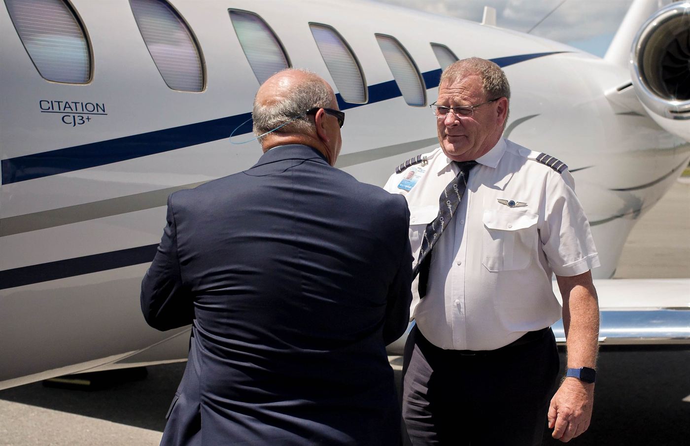 A flyExclusive captain greeting a Jet Club member beside a Citation CJ3+