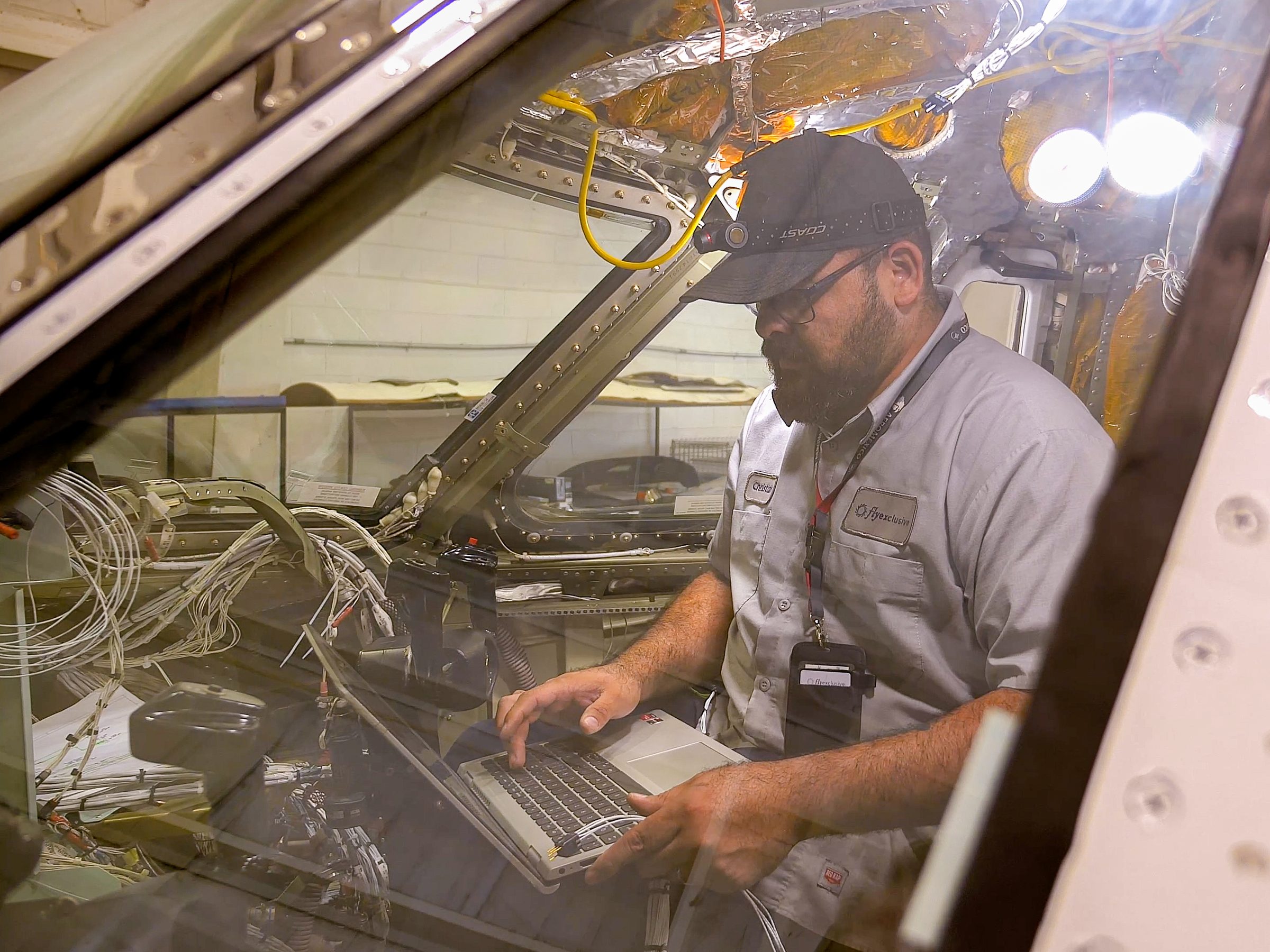 A flyExclusive avionics technician working from a laptop on the flight deck
