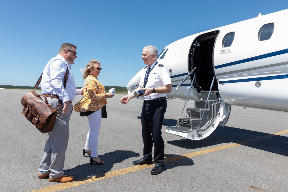 A flyExclusive captain greeting two members at the airstairs of a Citation