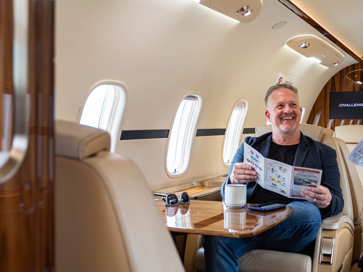A passenger seated at the table in a Challenger 350 cabin
