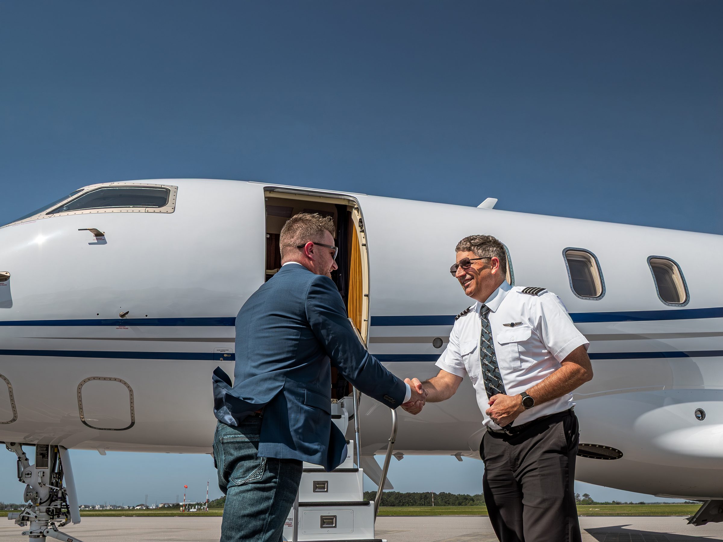 A flyExclusive captain greeting an owner at the airstairs of a Challenger 350