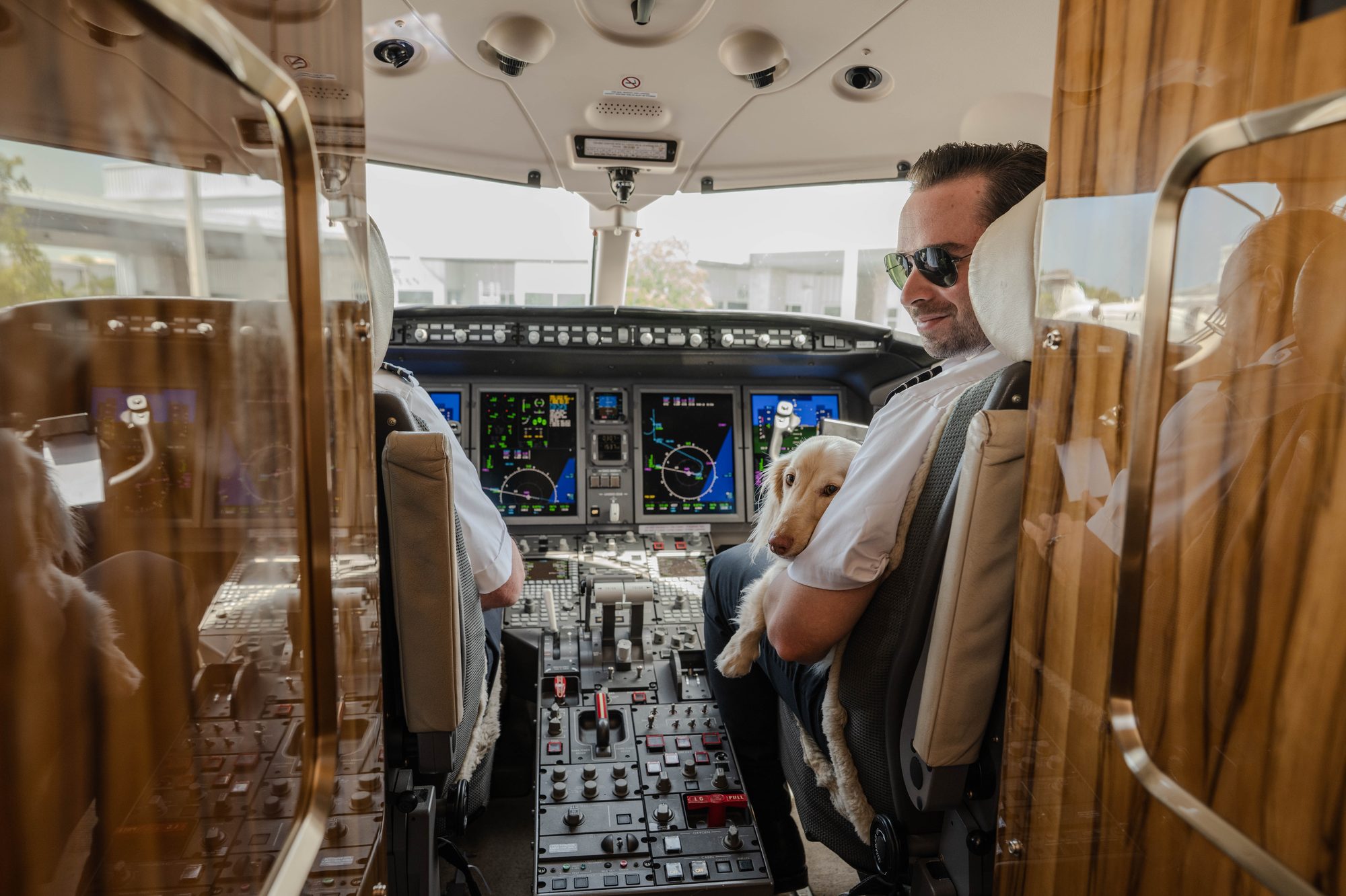 Two flyExclusive pilots at the controls, one holding a member&rsquo;s dog