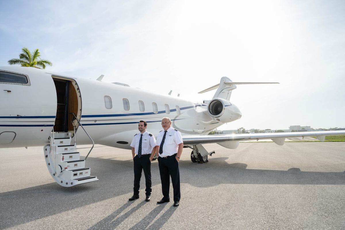 Two flyExclusive pilots on the ramp beside a Challenger 350, airstairs down
