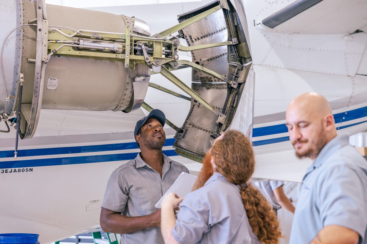 flyExclusive technicians at an open engine cowling in the maintenance hangar