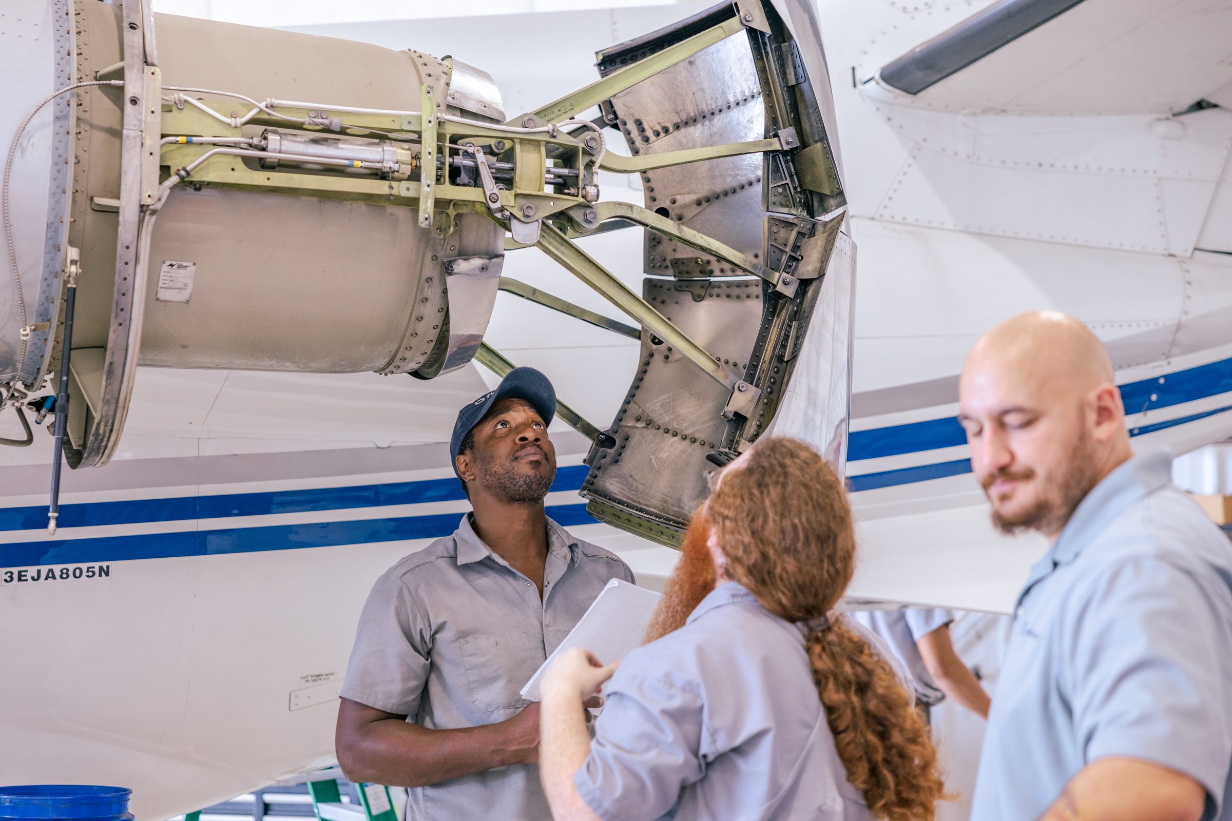 flyExclusive technicians at an open engine cowling in the maintenance hangar