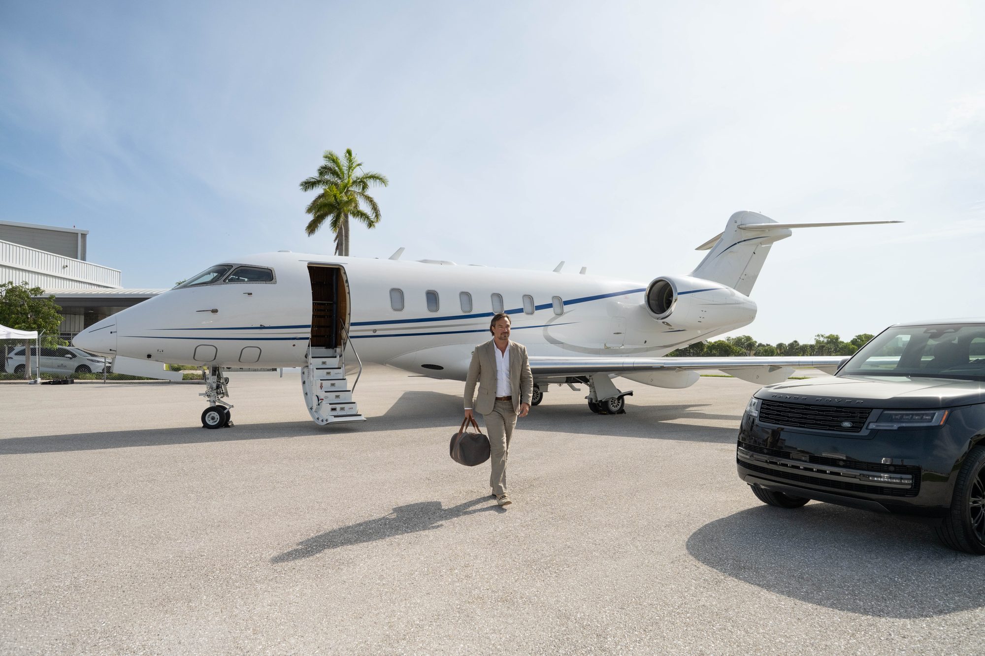 A traveller crossing the ramp from a flyExclusive Challenger 350 to a waiting car
