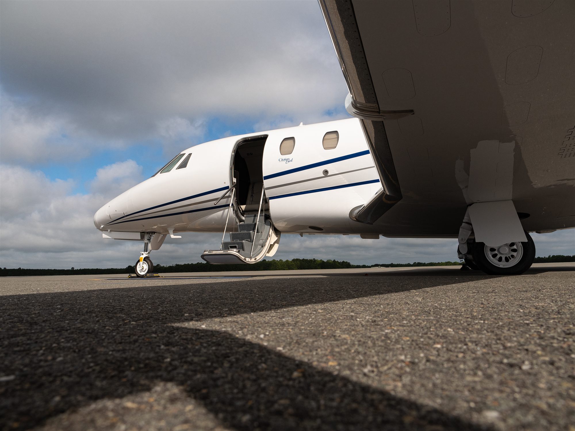 A flyExclusive Citation Excel seen from beneath the wing, airstairs down